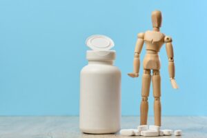 a woody dummy with a plastic bottle and oval white pills on a table, highlighting the withdrawal symptoms of gabapentin