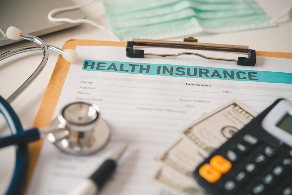 stethoscope and calculator placed on health insurance documents, begging the question, "does Medicaid cover rehab?